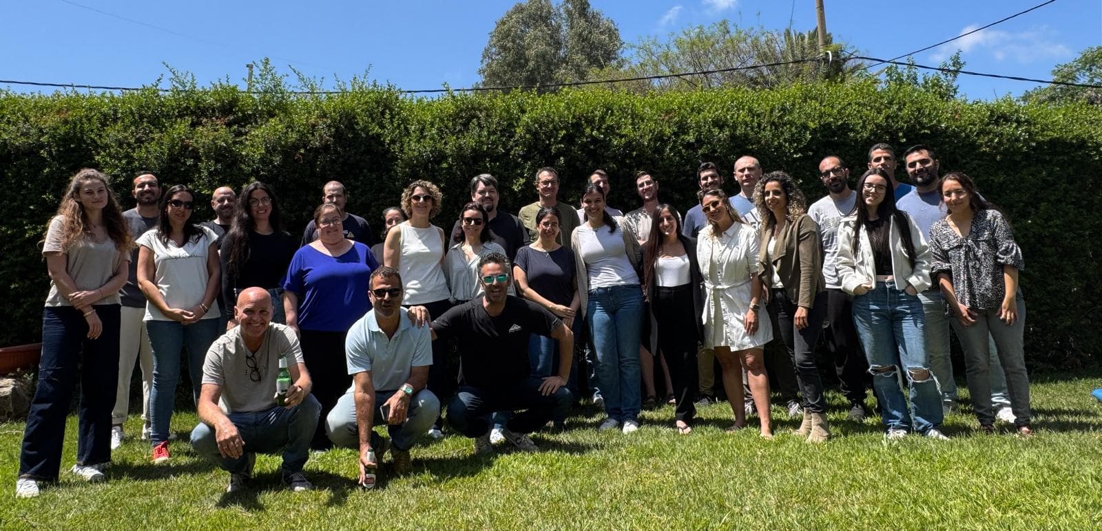 Tomax team posing together outdoors on a sunny day